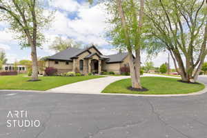 View of front of house with stone siding, curved driveway, and a front lawn
