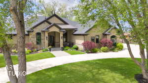 View of front facade with stucco siding, stone siding, a front lawn, and driveway