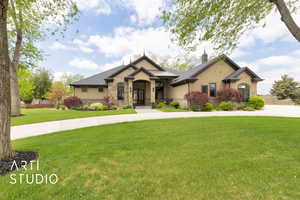 View of front of home featuring stone siding, a front yard, and stucco siding