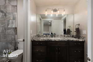 Bathroom with toilet, vanity, and a tile shower