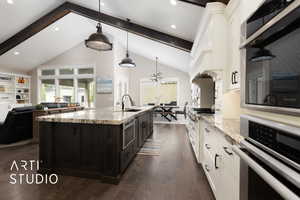 Kitchen featuring oven, a sink, white cabinets, beamed ceiling, and dark wood-style flooring