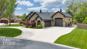 French country home featuring a gate, stone siding, a garage, and driveway
