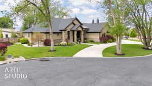 View of front facade featuring stone siding, a front lawn, and curved driveway