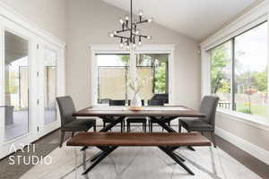 Dining area with vaulted ceiling, a chandelier, wood finished floors, and baseboards