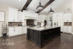 Kitchen with decorative backsplash, a breakfast bar area, white cabinetry, a sink, and recessed lighting