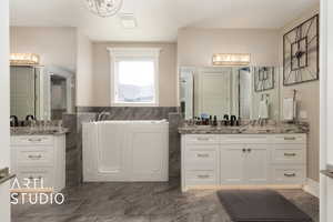 Bathroom with a bath, two vanities, and tile walls