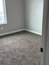 Carpeted empty room featuring baseboards