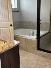 Full bath featuring a bath, vanity, and a shower with shower door