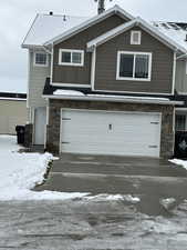 View of front of home featuring stone siding, a garage, concrete driveway, and board and batten siding