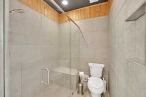 Full bath featuring toilet, a shower stall, tile walls, and recessed lighting