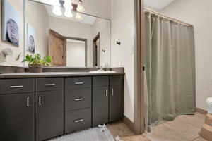 Full bathroom with double vanity, toilet, tile patterned flooring, and curtained shower