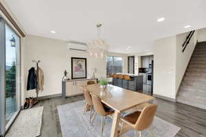 Dining area with stairs, an AC wall unit, wood finished floors, recessed lighting, and baseboards