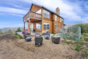 Rear view of property featuring a chimney, a wooden deck, board and batten siding, and a patio