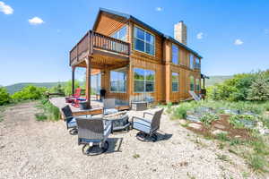 Rear view of house featuring an outdoor fire pit, a chimney, a vegetable garden, a deck, and board and batten siding
