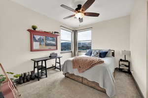 Carpeted bedroom featuring ceiling fan and baseboards