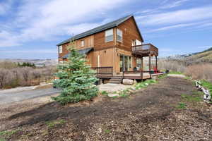 Back of property featuring a deck and roof with shingles
