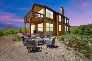 Rear view of property with a chimney, a vegetable garden, an outdoor fire pit, a wooden deck, and board and batten siding