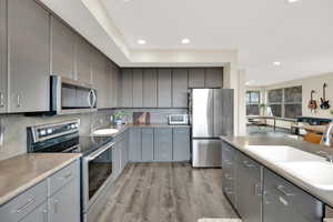 Kitchen featuring stainless steel appliances, gray cabinetry, a sink, and recessed lighting