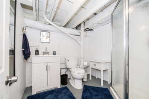 Full bathroom with finished concrete flooring, a shower stall, toilet, and vanity