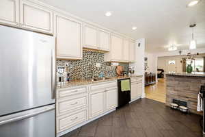 Kitchen with freestanding refrigerator, dishwasher, tasteful backsplash, recessed lighting, and light stone countertops