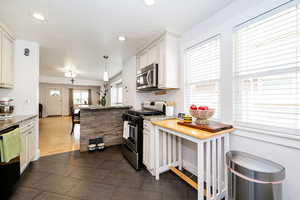 Kitchen featuring appliances with stainless steel finishes, a peninsula, recessed lighting, light stone countertops, and decorative light fixtures