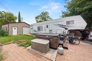 View of patio with an outdoor structure and a hot tub