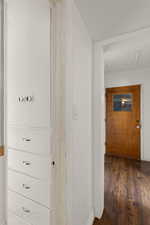 Hallway featuring hardwood / wood-style flooring, attic access, and baseboards