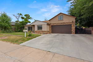 View of front of home with stucco siding, stone siding, and concrete driveway