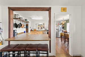 Kitchen featuring stainless steel appliances, a kitchen breakfast bar, wood finished floors, a sink, and tile countertops