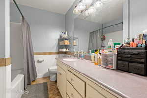 Full bath featuring vanity, toilet, wainscoting, shower / tub combo, and a chandelier