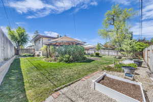 View of yard with a fenced backyard, a gazebo, and a vegetable garden