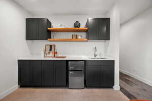 Bar featuring a sink, wet bar, freestanding refrigerator, and baseboards