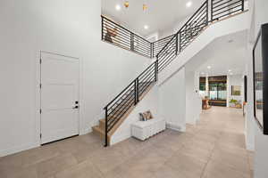 Entrance foyer featuring stairway, light tile patterned floors, and a high ceiling