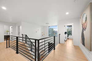 Hallway featuring an upstairs landing, light wood-type flooring, recessed lighting, and baseboards