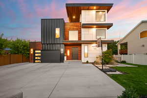 Modern home with a garage, fence, driveway, and a front yard