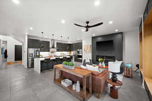 Living room with a glass covered fireplace, a ceiling fan, and recessed lighting