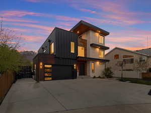 Contemporary house featuring driveway, an attached garage, board and batten siding, and fence