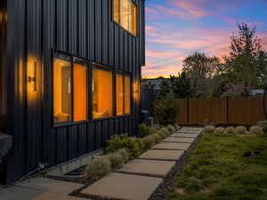 View of side of home with cooling unit, a lawn, board and batten siding, and fence