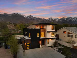 Contemporary house with concrete driveway, board and batten siding, a mountain view, fence, and a garage