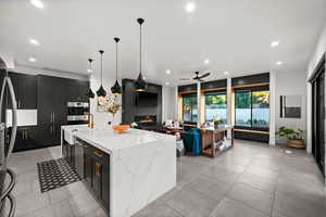 Kitchen with recessed lighting, light stone countertops, a sink, a ceiling fan, and open floor plan