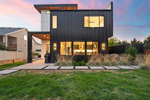 Back of house with a lawn, a patio, board and batten siding, and fence
