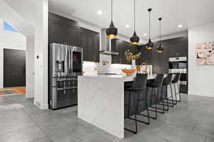 Kitchen with appliances with stainless steel finishes, light stone counters, recessed lighting, and a large island