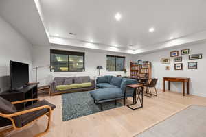 Living area featuring light wood-type flooring, recessed lighting, visible vents, and a tray ceiling
