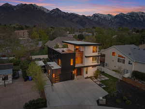 View of front facade with a mountain view, fence, a garage, and a balcony