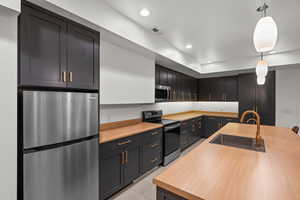 Kitchen with light tile patterned floors, a sink, appliances with stainless steel finishes, recessed lighting, and decorative light fixtures