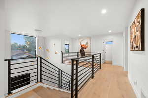 Corridor with an upstairs landing, visible vents, a healthy amount of sunlight, and recessed lighting