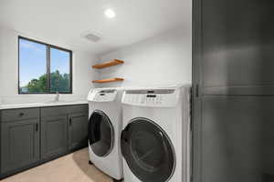 Laundry area featuring recessed lighting, washer and dryer, cabinet space, and a sink