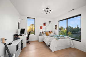 Bedroom with baseboards, visible vents, a notable chandelier, and light wood-style floors