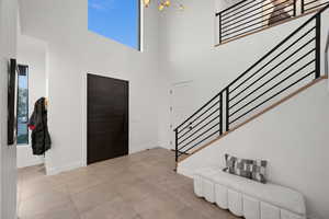 Entryway with a towering ceiling, baseboards, light tile patterned floors, and stairs