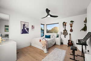 Bedroom featuring baseboards, a ceiling fan, and light wood-style floors